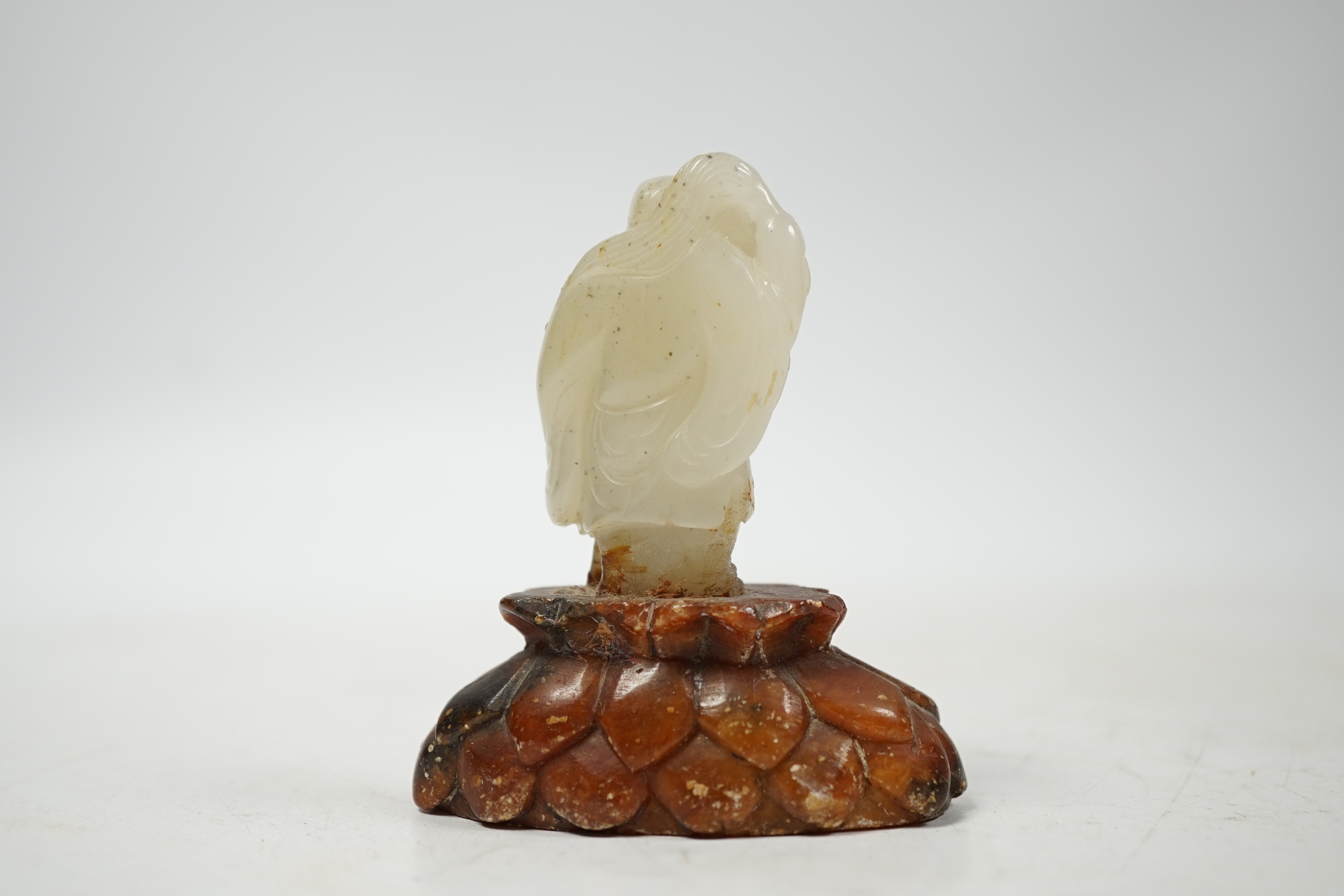 A Chinese pale celadon jade figure of a man holding a fly whisk, Qing dynasty, 5.2cm high, soapstone stand, total height 8cm high